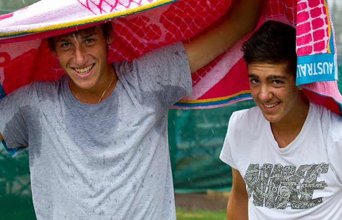 Daniel Guccione (L) and Thanasi Kokkinakis try to keep dry during a rain delay in Bendigo; Tennis Australia